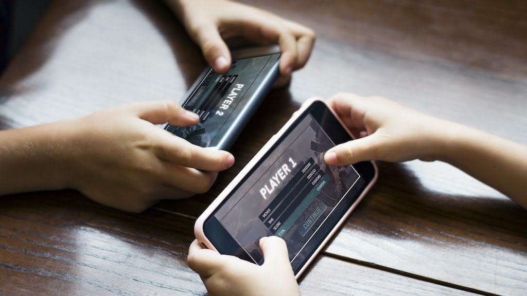 Two people holding cell phones next to each other playing a game