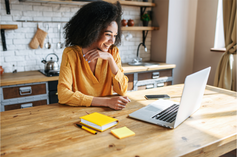 Woman sitting at her kitchen table on a vidoe conference call on her computer using Webex