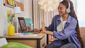 Woman at her desk wearing Cisco headset and waving hello