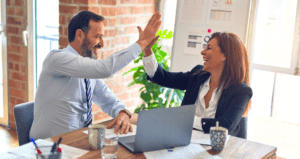 Two Coworkers With Excellent Soft And Collaboration Skills High-fiving In Office | Feature