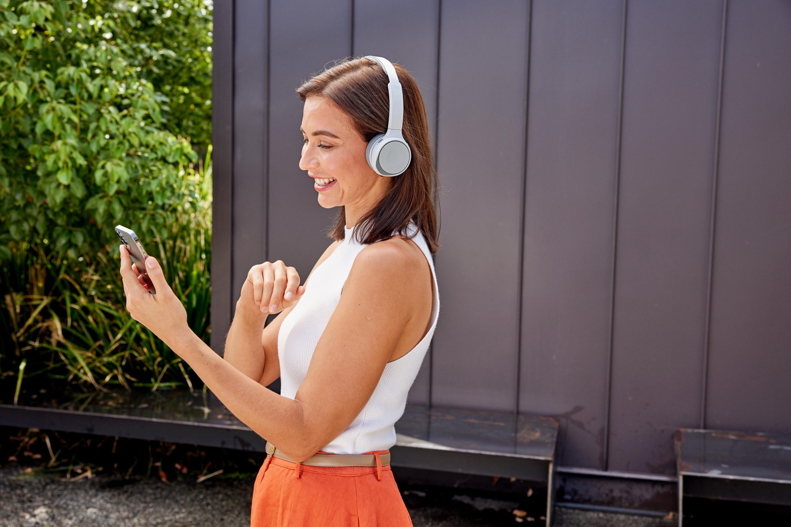 Mulher usando fones de ouvido Cisco fazendo uma chamada em um ambiente externo