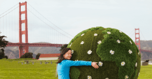 Person hugging a bush in front of the San Francisco Bridge