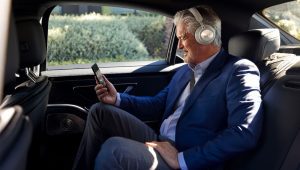 Man traveling in back of car on phone with Cisco headsets