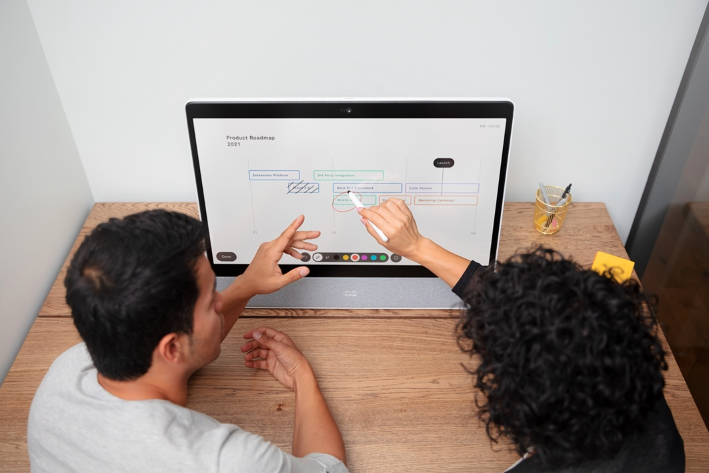 Zwei Kollegen arbeiten gemeinsam an einem Touchscreen-Gerät für die Zusammenarbeit