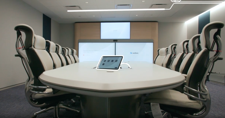 一间办公室，中间有一张桌子，展示了混合办公视频会议的理想设置。 