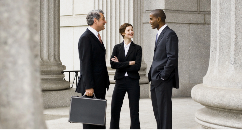 Three people standing at a courthouse