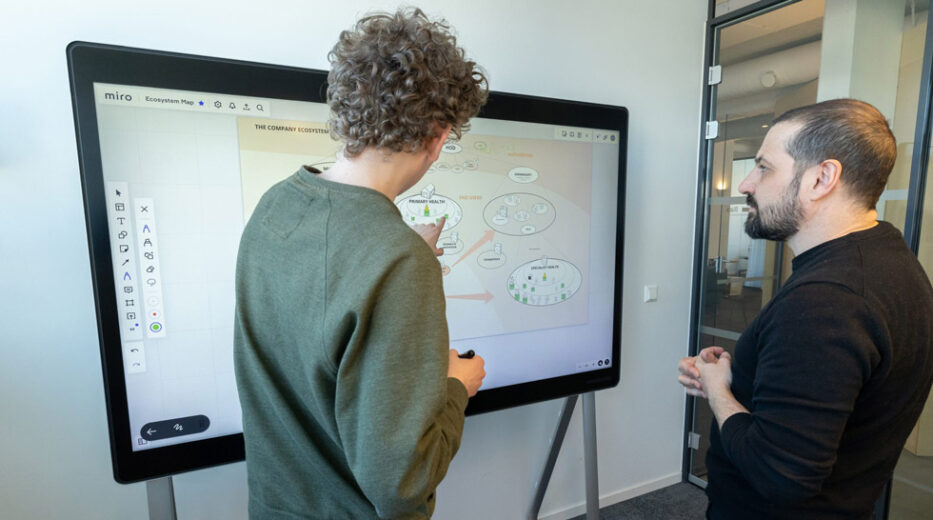 Two Designit team members collaborate on a project using Miro on a Webex Board