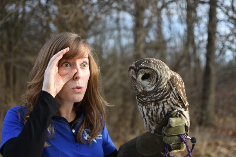 A person holds an owl and impersonates their eyes