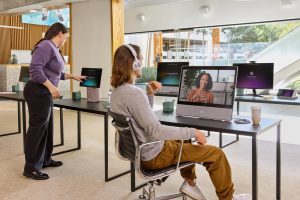 Two Cisco Employees In The Office Using Various Cisco Products Including The Webex Desk Pro