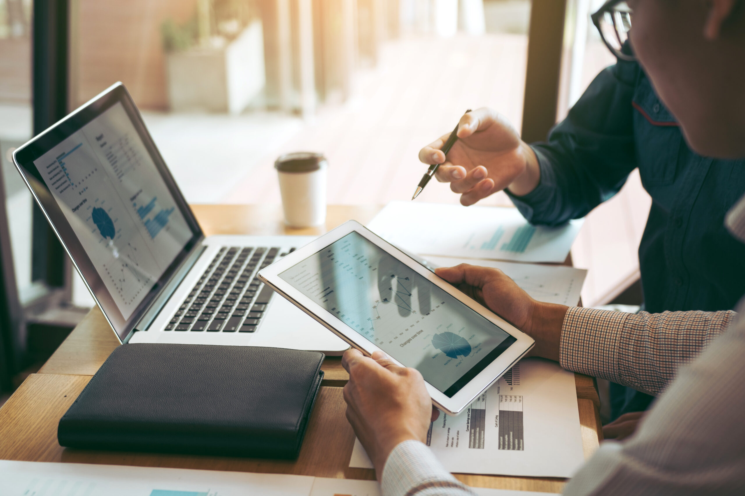 Business partnership coworkers using a tablet to chart company financial statements report and profits work progress and planning in office room.