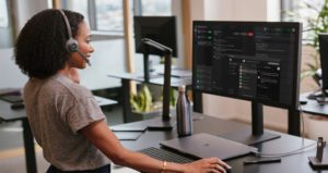 Woman At Desk With Headphones, Talking On Webex App