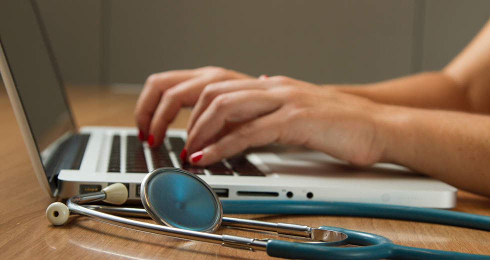 Healthcare Professional Working On Laptop With Stethoscope In View, While Video Conferencing With Webex | Feature